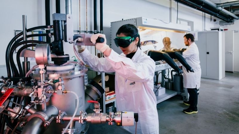 Scientists in lab coats operating advanced laboratory equipment in a research facility.
