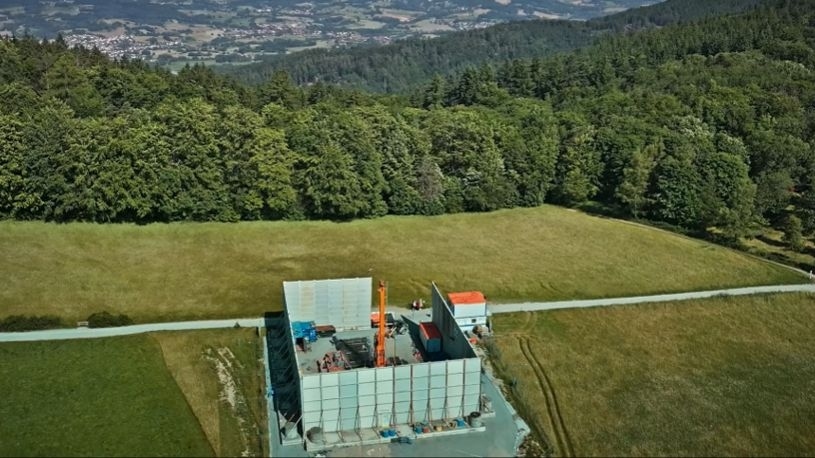 A construction site for exploratory drilling with scaffolding and a crane in a rural, forested landscape in the Tromm region of the Odenwald in Hesse