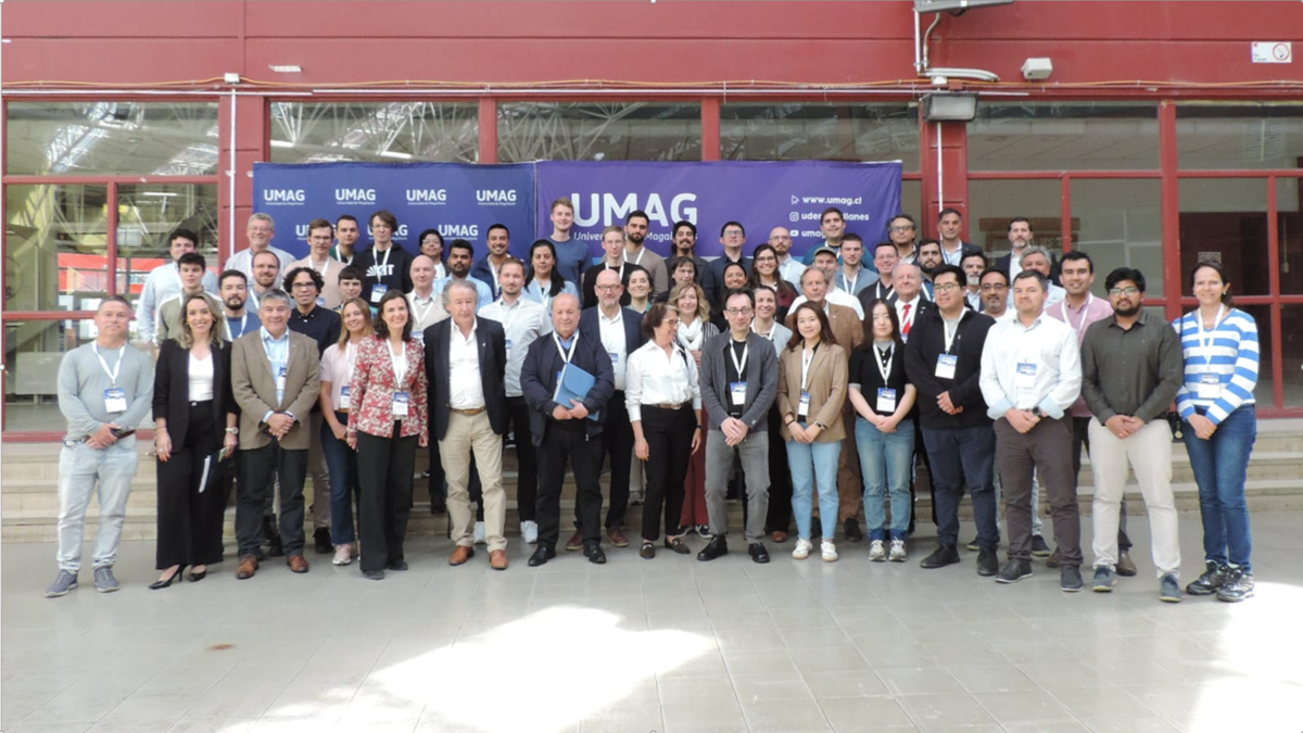 Group of people posing in front of a building with a UMAG banner in the background.